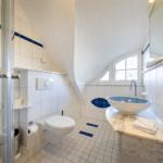 Badezimmer mit Dusche, Toilette und Waschbecken auf Marmorplatte.