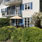 Wohnhaus mit Balkon und Gartenbereich mit Sonnenschirm und Sitzgelegenheit.