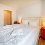 Ein Schlafzimmer mit Doppelbett, zwei Nachttischen und einer Tür.