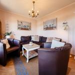 Wohnzimmer mit Ledersofa, Beistelltisch und weißen Wandschränken.