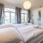 Schlafzimmer mit Doppelbett, Fenstern und Kleiderschrank.