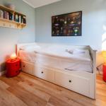Schlafzimmer mit weißem Bett, Holzboden und roten Nachttischen.