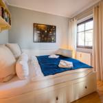 Schlafzimmer mit Bett, Bücherregal, Fenster und Kleiderschrank.