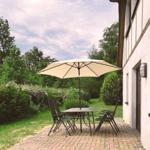Terrasse mit Tisch, Stühlen und Sonnenschirm neben Hauswand.