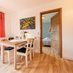 Esszimmer mit Tisch, Stühlen und Blick in Schlafzimmer. Holzfußboden und Wandbild.