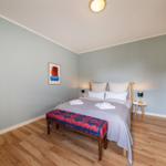 Schlafzimmer mit Bett, Holzboden und Wandbild.