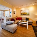 Wohnzimmer mit Sofa, Couchtisch und Essbereich. Holzboden und Wandbild sichtbar.