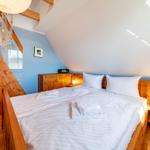 Schlafzimmer mit Doppelbett, Holzmöbel und Dachschrägen. Blaue Wand und Fenster.