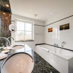 Badezimmer mit Badewanne, Waschtisch und Fenster