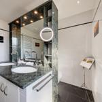Doppelwaschbecken mit dunklem Marmor, Spiegelschrank und runden Spiegel.