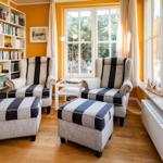 Zwei Sessel mit Füßen und ein Bücherregal an der Wand.