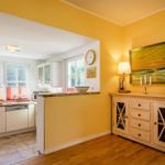 Küche mit Arbeitsplatte und Fenster. Wohnbereich mit Sideboard und Wandbild.