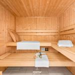 Holzsauna mit Bänken, Handtüchern und Saunakissen.