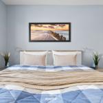 Schlafzimmer mit Bett, Wandbild und Nachttischen.