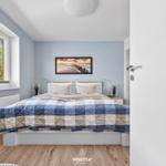 Schlafzimmer mit Bett, Fenster und Wandbild.