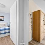 Schlafzimmer mit Bett und Wandbild. Flur mit Kleiderschrank und Tisch.