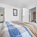 Schlafzimmer mit Bett, Fernseher und Blick in Bad und Kleiderschrank.