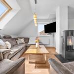 Wohnzimmer mit Sofa, Couchtisch und Kaminofen unter Dachschrägen.