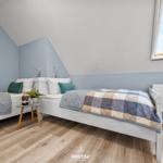 Zimmer mit zwei Betten, Holzboden und Dachfenster. Wandfarbe blau-weiß.