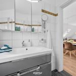 Badezimmer mit Waschbecken, Spiegelschrank und Blick in Essbereich.