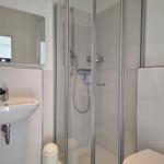 Badezimmer mit Dusche, Waschbecken und Toilette.