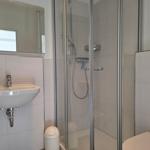 Badezimmer mit Dusche, Waschbecken und Spiegel
