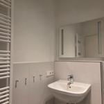 Badezimmer mit Waschbecken, Spiegel und Heizkörper an der Wand.