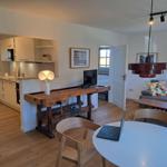 Wohnküche mit Holzboden, Sofa, Esstisch und Arbeitsplatz.