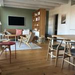 Wohn- und Essbereich mit Holzboden, Sofa, Fernseher und Esstisch mit Stühlen.