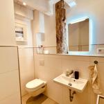 Bathroom with toilet, sink, and lit mirror