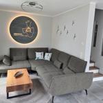 Wohnzimmer mit grauem Sofa, Holztisch und Wanddekoration.