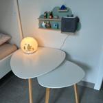 Schreibtisch mit Lampe und Regal an Wand, daneben Bett