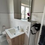 Badezimmer mit Waschbecken, Spiegel, Toilette und Heizkörper