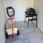 Räumlichkeiten mit Grill, Kinderwagen und Schlauch an der Wand.