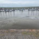Hafen mit Booten und Watt bei Ebbe. Blick von gepflastertem Ufer.