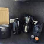Küchenbereich mit Toaster, Kaffeemaschine und Wasserkocher auf dunkler Arbeitsfläche.