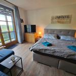 Bedroom with balcony view. Bed, TV, and nightstands.