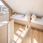 Zwei Einzelbetten unter Dachschräge mit Fenster und Holzboden.