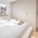 Schlafzimmer mit Doppelbett, Fenster und Schlafzimmerausgang.