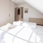 Schlafzimmer mit Dachschrägen, Bett mit weißen Laken und Handtüchern.