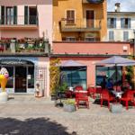 Gelateria mit Sitzgelegenheiten und farbenfrohen Gebäuden im Hintergrund.