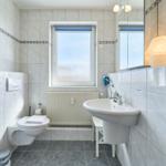 Badezimmer mit Dusche, Toilette, Waschbecken und Fenster.