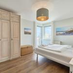 Schlafzimmer mit Bett, Kleiderschrank und Fenster zum Balkon.