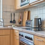 Küche mit Spüle, Herd, Kühlschrank und Küchenutensilien.