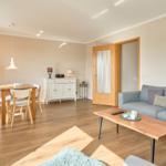 Wohn- und Essbereich mit Holzboden, Sofa, Tisch und Stühlen.