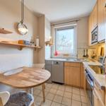 Küche mit Essbereich, Holztisch, Spüle und Fenster.