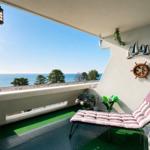 Terrasse mit Liegestuhl und Meeresblick. Wanddekoration mit Segelbooten, Ruder und Anker.