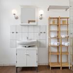 Bathroom with sink, mirror, shower, and wooden shelf with towels.