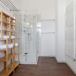 Bathroom with shower, sink, and wooden shelf.