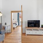 Living room with sofa, TV, and view into the bedroom.